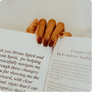 Freshly manicured, natural-shaped nails resting on the pages of an open book